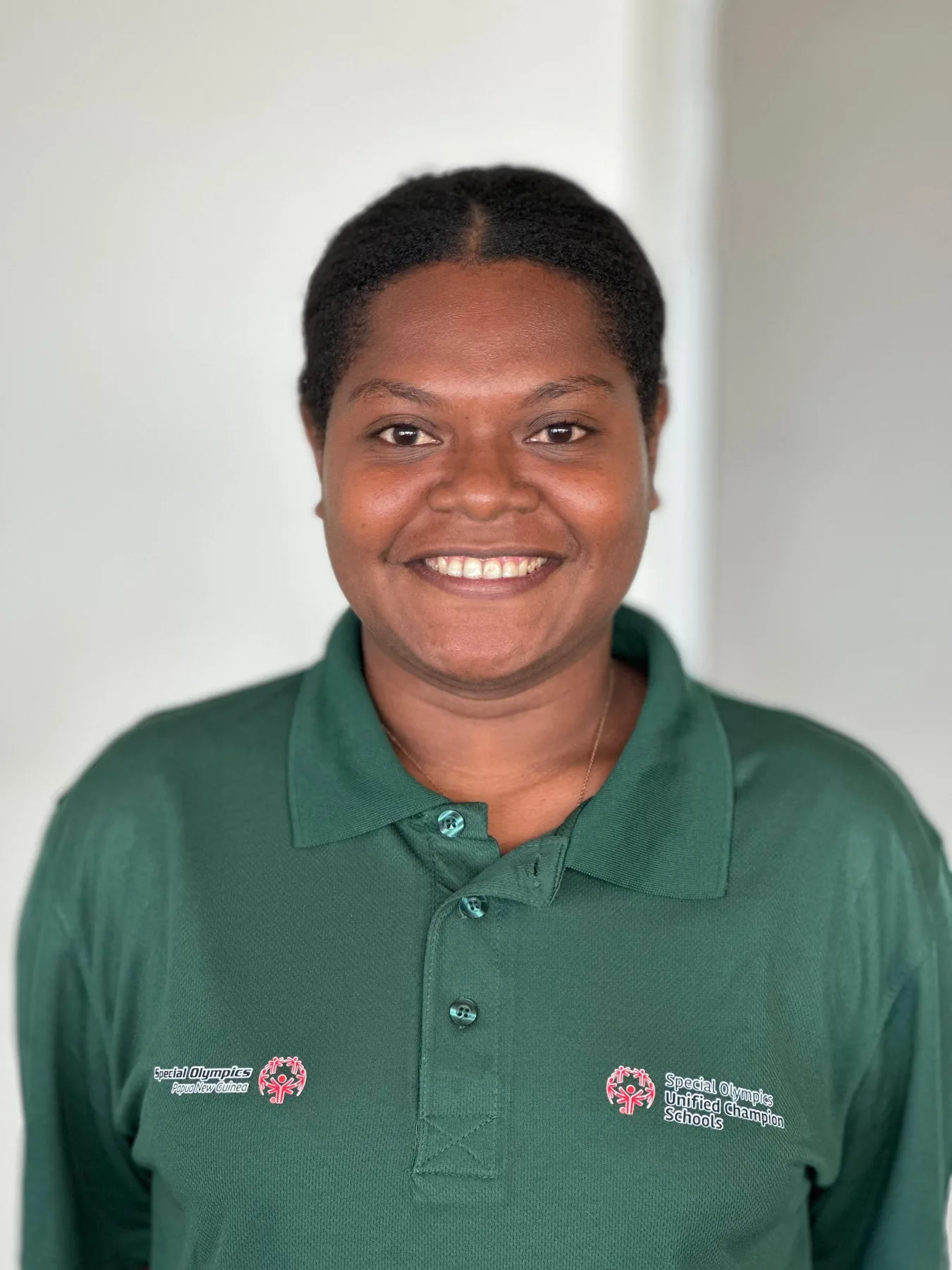 SOPNG volunteer team member smiles in a green organization shirt